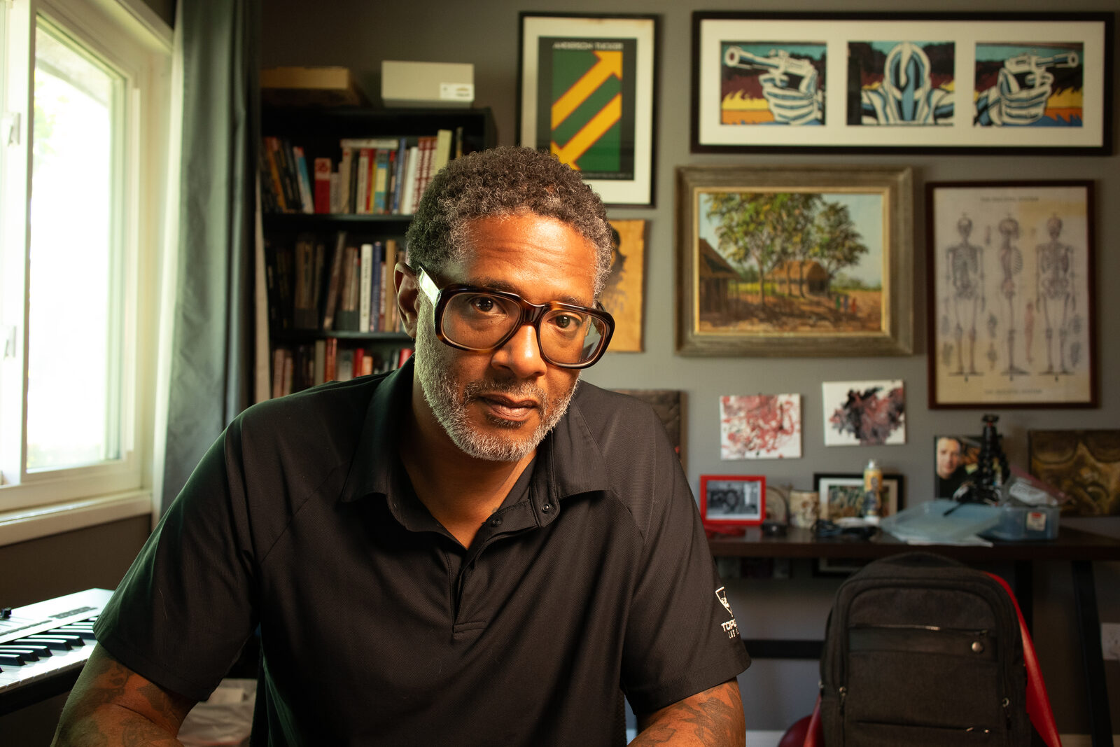 Miguel Collins seated in his home studio, surrounded by framed art and books